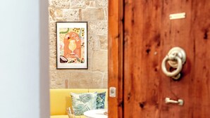 A room with a stone wall, a framed picture, a yellow sofa, and a wooden door. - Pina Colada- New apartment in the historic center of Siena (Siena)