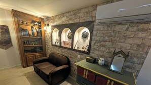 A cozy room with a leather armchair, a bookshelf, a wall-mounted mirror, and a dresser with multiple drawers. - The Sorcerer's Den (Caumont-sur-Durance)