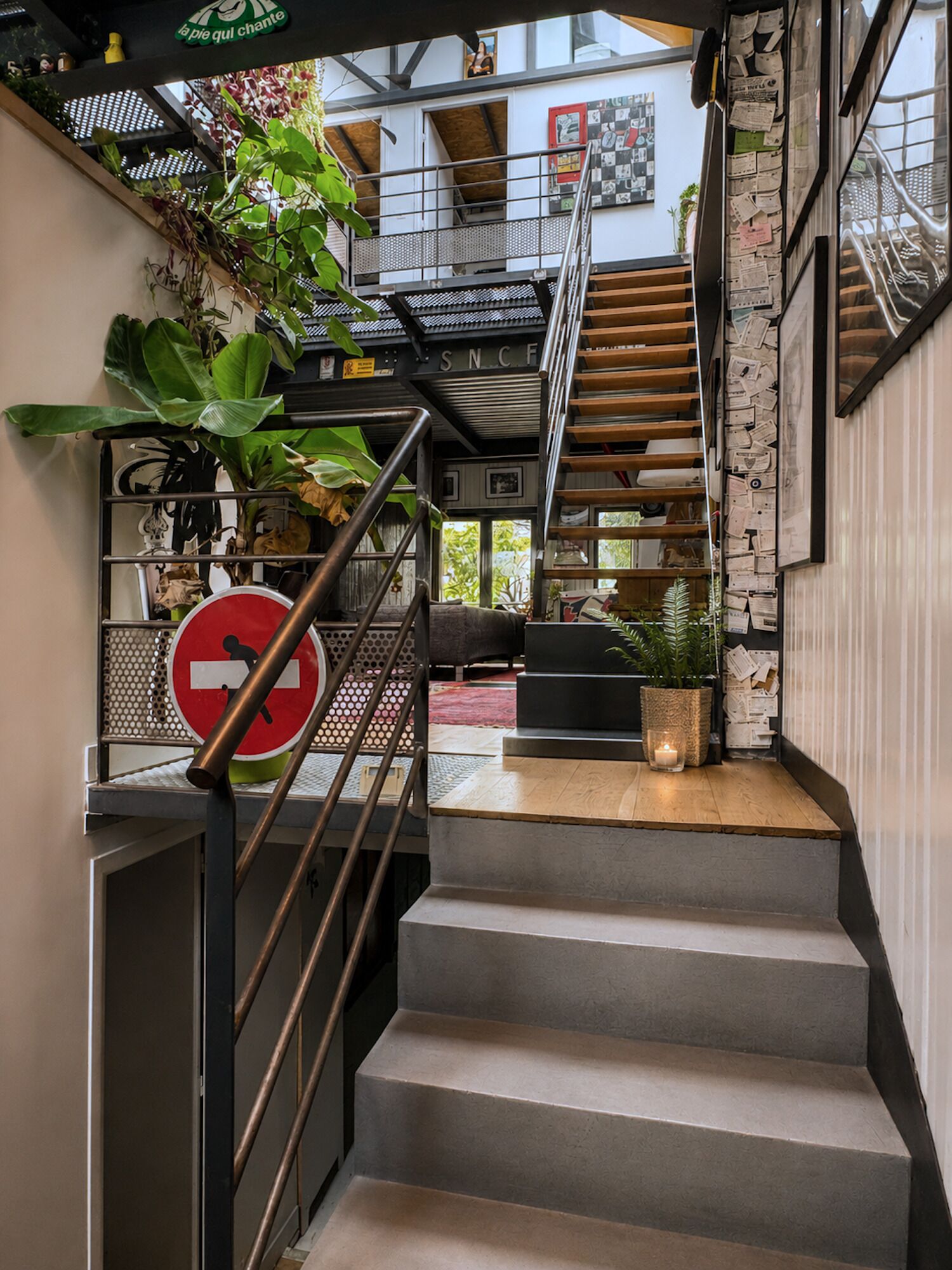 Un escalier avec une rampe métallique, un panneau indiquant «accès interdit» et une plante sur le palier.