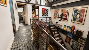 A staircase with a metal railing, a wall with various posters, and a skylight above. - Villa Georges (Issy-les-Moulineaux)