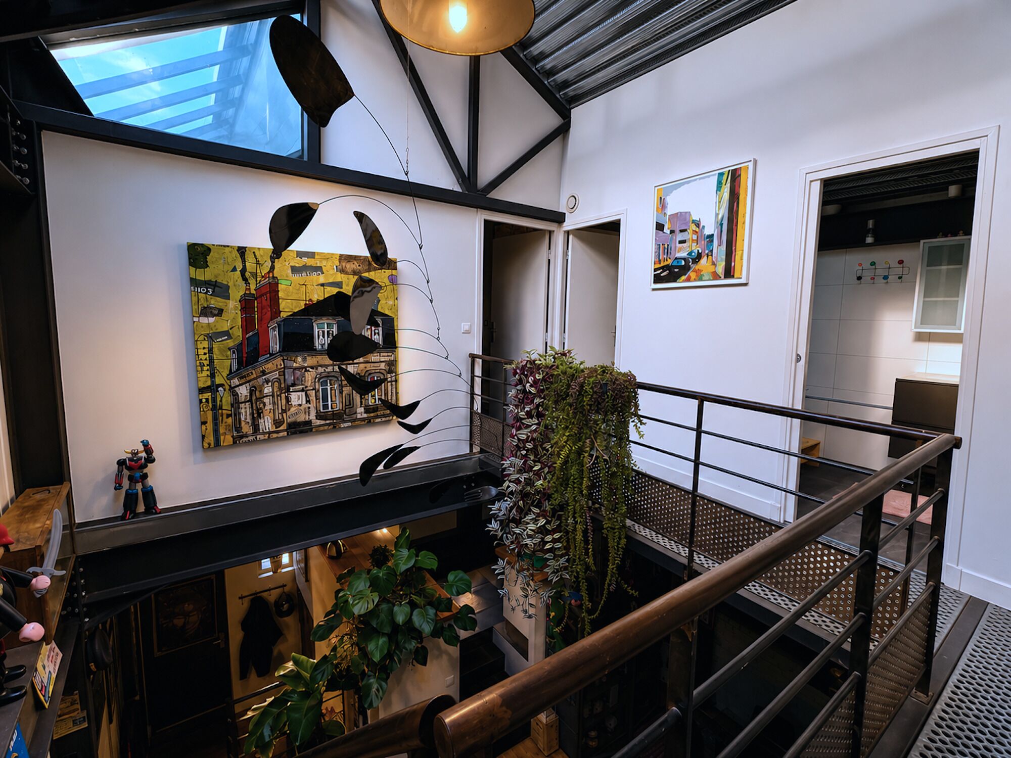 Een meerlaags interieur met een trap, kunst aan de wanden en een plant.