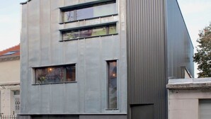A modern building with a metal exterior, large windows, and a garage door.