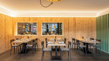 Ein Restaurant mit Holzwänden, großen Fenstern und mehreren Tischen und Stühlen.