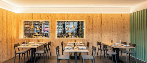 A restaurant with wooden walls, large windows, and multiple tables and chairs.