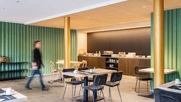 Un café moderno con techo de madera, paredes verdes y una barra con productos para el desayuno.