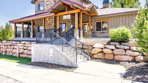 A two-story house with a stone facade, a covered porch, and a staircase leading to the entrance. - Peak Location Near Slopes & Olympic Park (Park City)