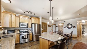 A kitchen with granite countertops, stainless steel appliances, wooden cabinets, and a central island with bar stools. - Peak Location Near Slopes & Olympic Park (Park City)