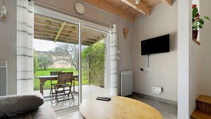 Een woonkamer met een bank, een houten tafel, een aan de muur bevestigde televisie en een schuifdeur die leidt naar een terras.