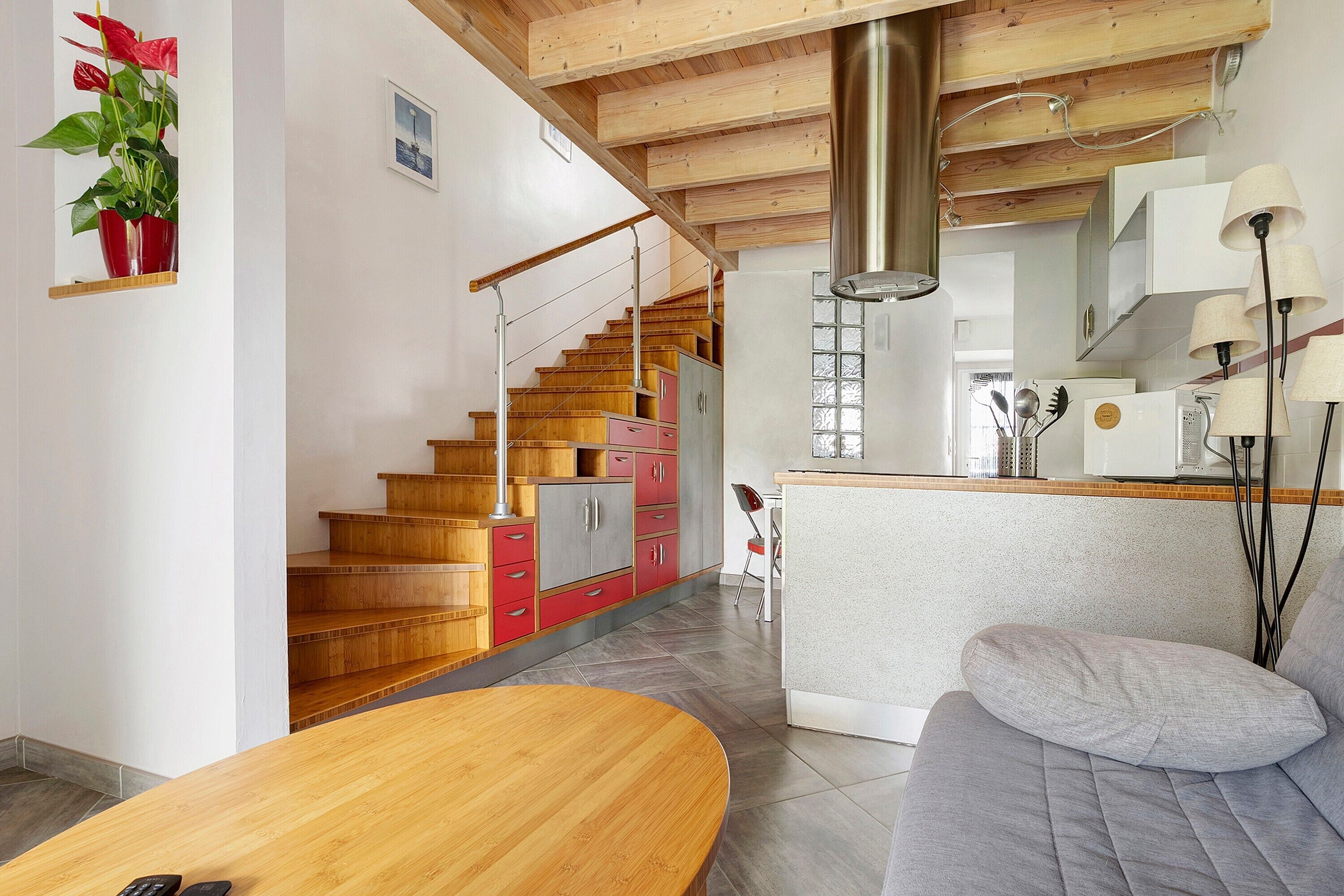 A modern kitchen with wooden cabinets, a built-in stove, and a dining area with a wooden table and sofa.