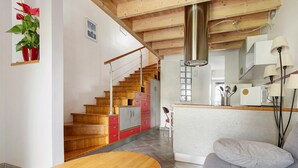 Een moderne keuken met houten kastjes, een inbouwfornuis en een zithoek met een houten tafel en een bank.