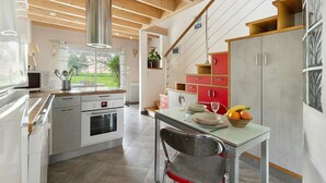 Een moderne keuken met houten balken, roestvrijstalen apparatuur en een eethoek met een tafel gedekt voor twee personen.