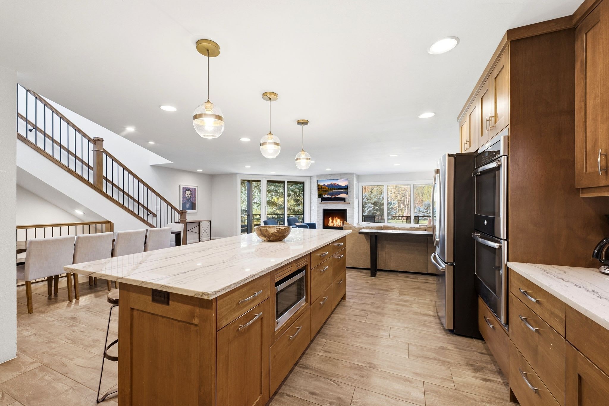 A modern kitchen with wooden cabinets, a marble island, and a built-in oven.