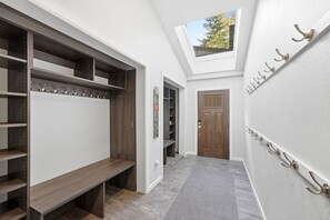 A hallway with a built-in bench, a coat rack, a door, and a skylight. - Snowcap Lodge | Sauna, Hot Tub & Mountain Fun (Park City)