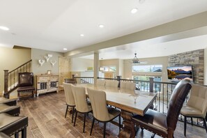 A spacious dining area with a large table and chairs, a wooden cabinet, and a staircase leading to an upper level. - Family Friendly Townhouse with Private Hot Tub (Park City)