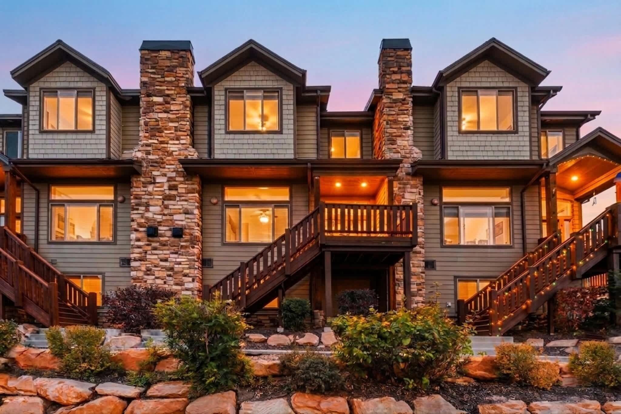 A multi-story house with a stone facade, multiple windows, and a wooden staircase.