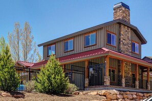 A two-story house with a stone chimney, large windows, and a covered porch. - Family Friendly Townhouse with Private Hot Tub (Park City)