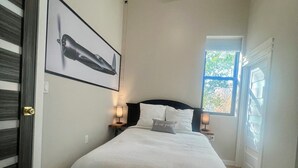 A bedroom with a bed, a ceiling fan, a window, and a framed picture on the wall. - New renovation retro-Modern 1960s Service Station • Fireplace • 100″ TV•garage (Nunica)
