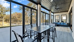 Eine großzügige Terrasse mit Esstisch und Stühlen, einer Sitzecke und einem Deckenventilator.