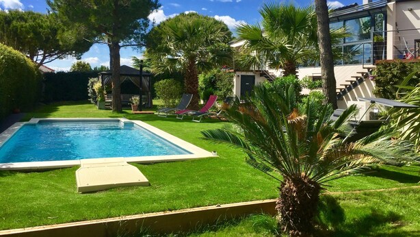 A swimming pool surrounded by a well-maintained lawn, palm trees, and a gazebo. - L'ESCALE COTE BLEUE VILLA & Spa 4étoiles (Sausset-les-Pins)