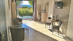 A modern room with a glass table, two chairs, a sofa, a view of the sea, and a wooden cabinet. - L'ESCALE COTE BLEUE VILLA & Spa 4étoiles (Sausset-les-Pins)