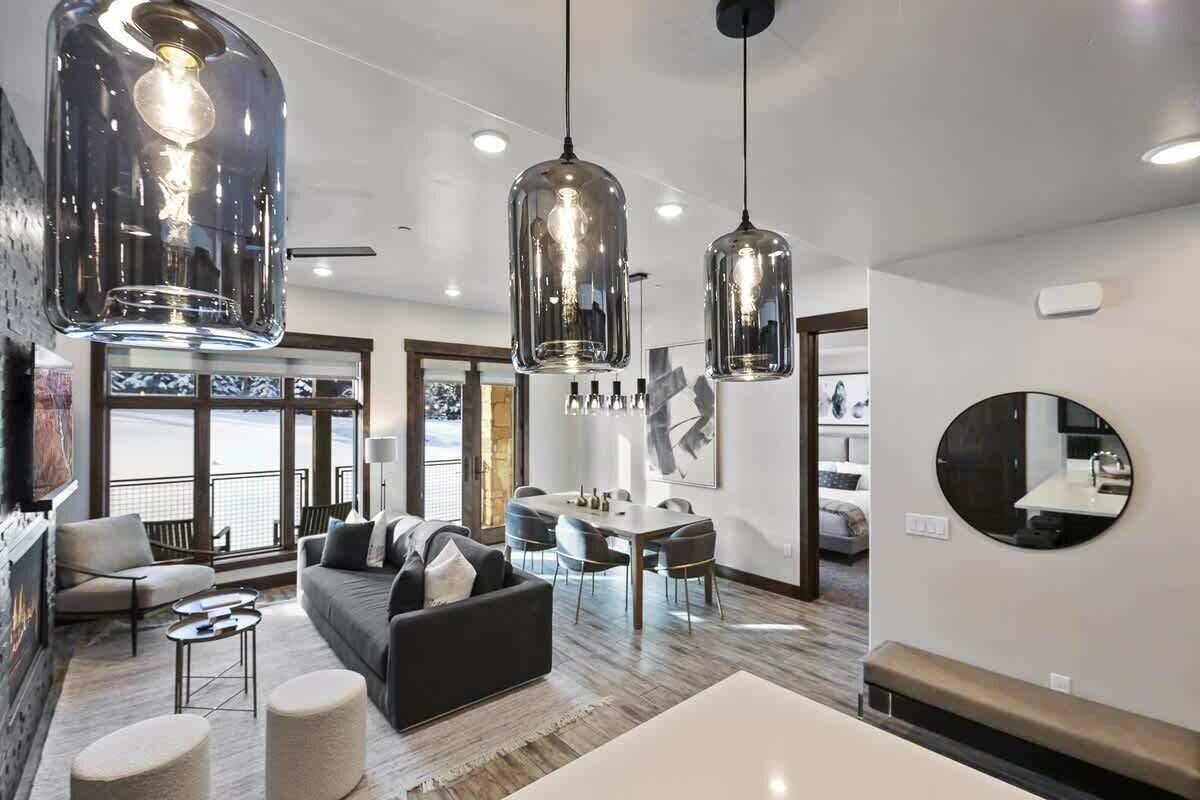 A modern living room with a sofa, ottomans, and a dining area with a table and chairs.
