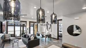 Una sala de estar moderna con un sofá, otomanas y un comedor con una mesa y sillas.