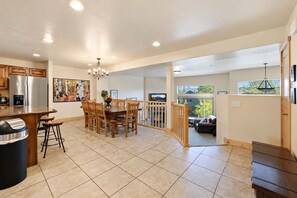 A spacious kitchen with a dining area, a fireplace, and a view to a balcony. - Bears Lair | Private Hot Tub & Mountain Views (Park City)