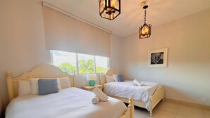 Ein Hotelzimmer mit zwei Betten, einem Fenster mit Blick auf Grünflächen und einem gerahmten Bild an der Wand.