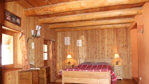 Una habitación de madera con una cama, mesitas de noche y un aparador.