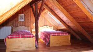 Un dormitorio acogedor en el ático con dos camas de madera, techo de madera y techo inclinado.