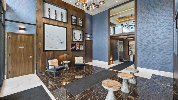 A modern lobby with a wooden reception desk, seating area, and a staircase leading to upper floors. - New! Luxe Studio + Patio | Trails, Lake & Adventure | Free shuttle to Gondola (Park City)