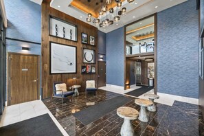 A modern lobby with a wooden reception desk, seating area, and a staircase leading to upper floors. - New! Luxe Studio + Patio | Trails, Lake & Adventure | Free shuttle to Gondola (Park City)