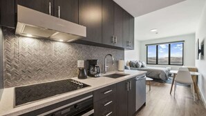 A modern kitchen with dark cabinets, a herringbone backsplash, and a built-in stove. - New! Lux Studio Lake Views | Trails & Adventure | Free shuttle to Gondola (Park City)