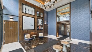 A modern lobby with a wooden reception desk, seating area, and a staircase leading to upper floors. - New! Lux Studio Lake Views | Trails & Adventure | Free shuttle to Gondola (Park City)