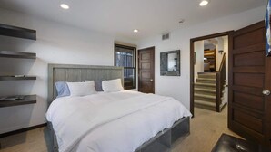 A bedroom with a large bed, a wooden headboard, a bedside table, and a wardrobe. - Charming Chalet in Old Town & Pet Friendly (Park City)