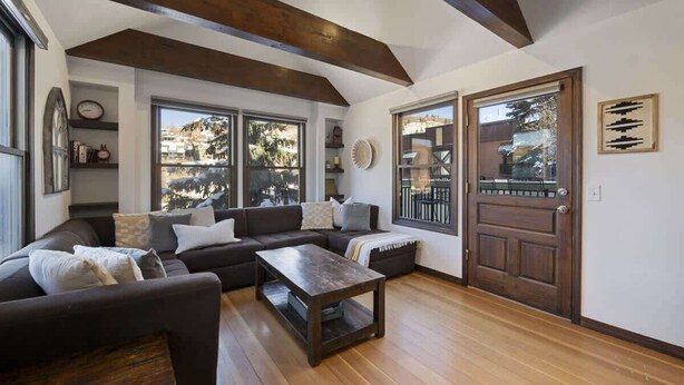 A living room with a dark brown sofa, a wooden coffee table, and a wooden door. - Charming Chalet in Old Town & Pet Friendly (Park City)