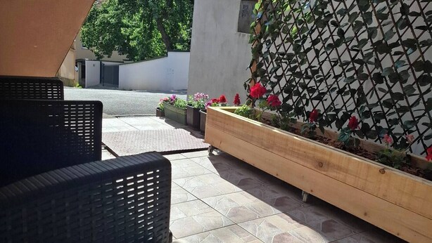 Un espace extérieur aménagé avec des meubles en osier et un jardinier orné de fleurs.
