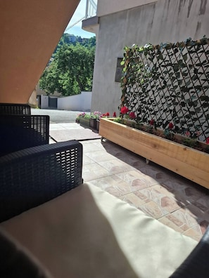 Un espace extérieur aménagé avec des meubles en osier et un jardinier orné de fleurs.