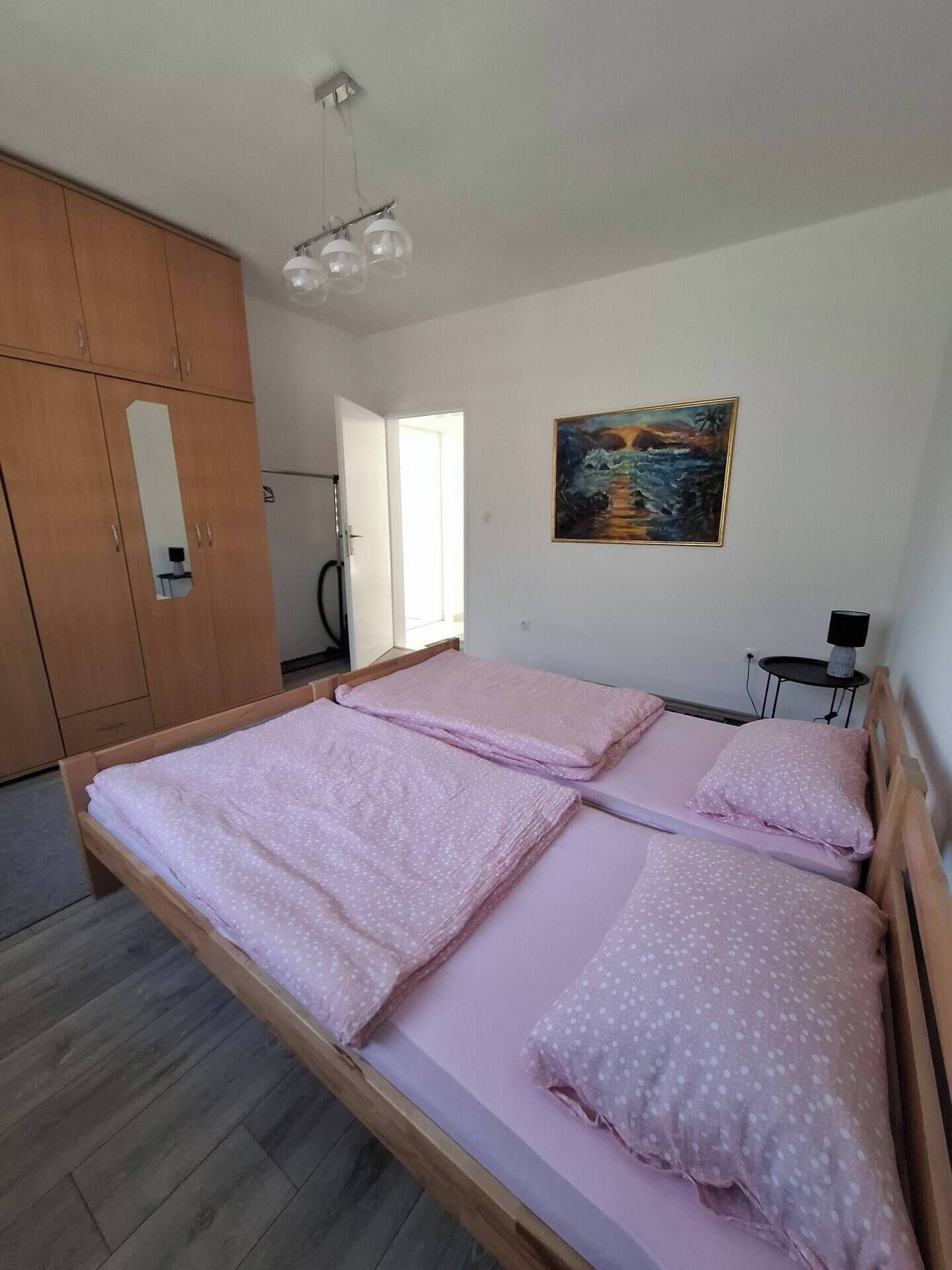 A bedroom with a wooden bed, a painting on the wall, and a wardrobe.