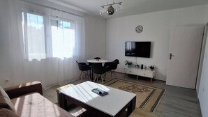 Un salon comprenant un canapé, une table basse, un téléviseur et un coin repas avec des chaises et une table.