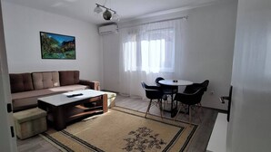 Un salon moderne avec un canapé marron, une table basse et un coin repas comprenant une table et des chaises.