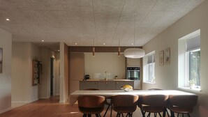 Une cuisine moderne dotée d’un îlot central, de luminaires suspendus et d’un coin repas avec des chaises en bois.