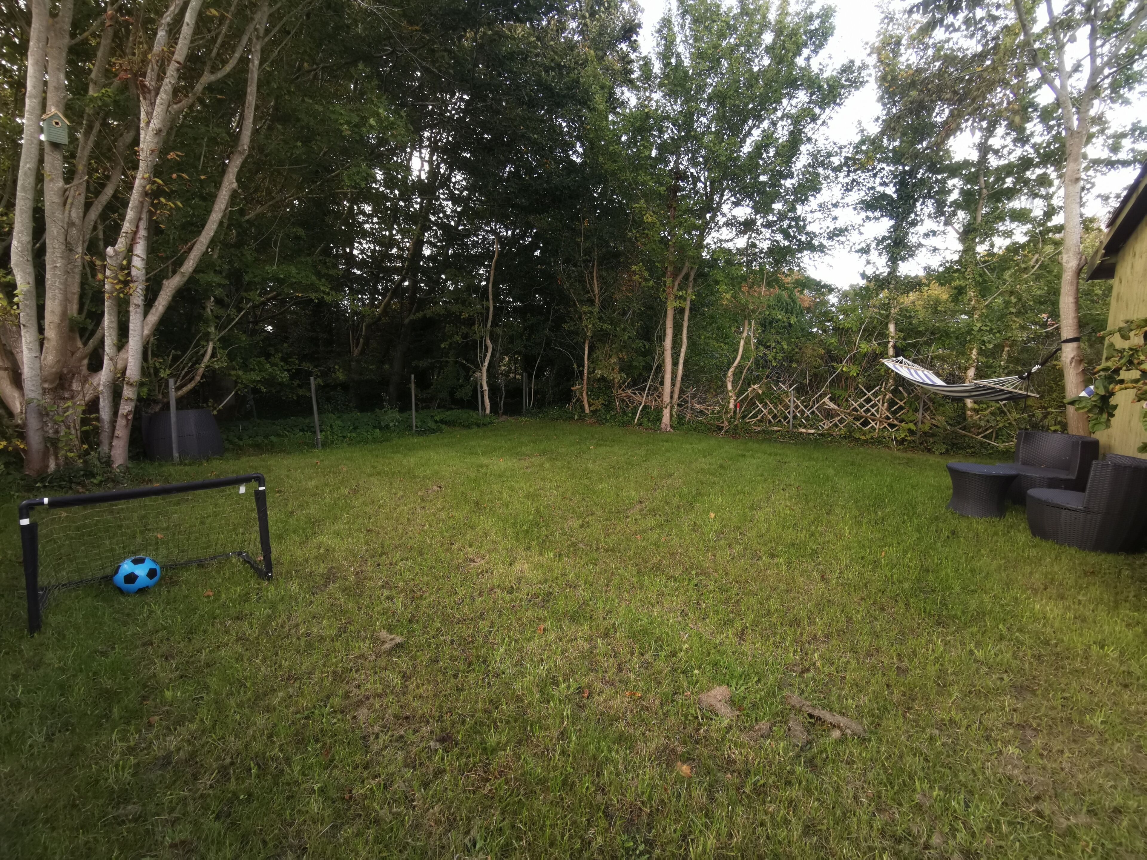 Een gazon met een voetbaldoel, een hangmat en tuinmeubilair.