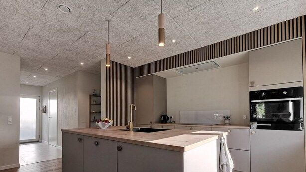 Une cuisine moderne dotée d’un îlot central, d’un four encastré et d’une grande fenêtre.