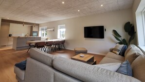 Un salon moderne avec un canapé gris, une table basse et un téléviseur fixé au mur.