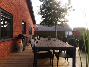 A patio with a wooden table and chairs, a barbecue grill, and a trash can. - Cozy 4-bedroom Holiday Home in Vesterø Havn, Denmark (Læsø)