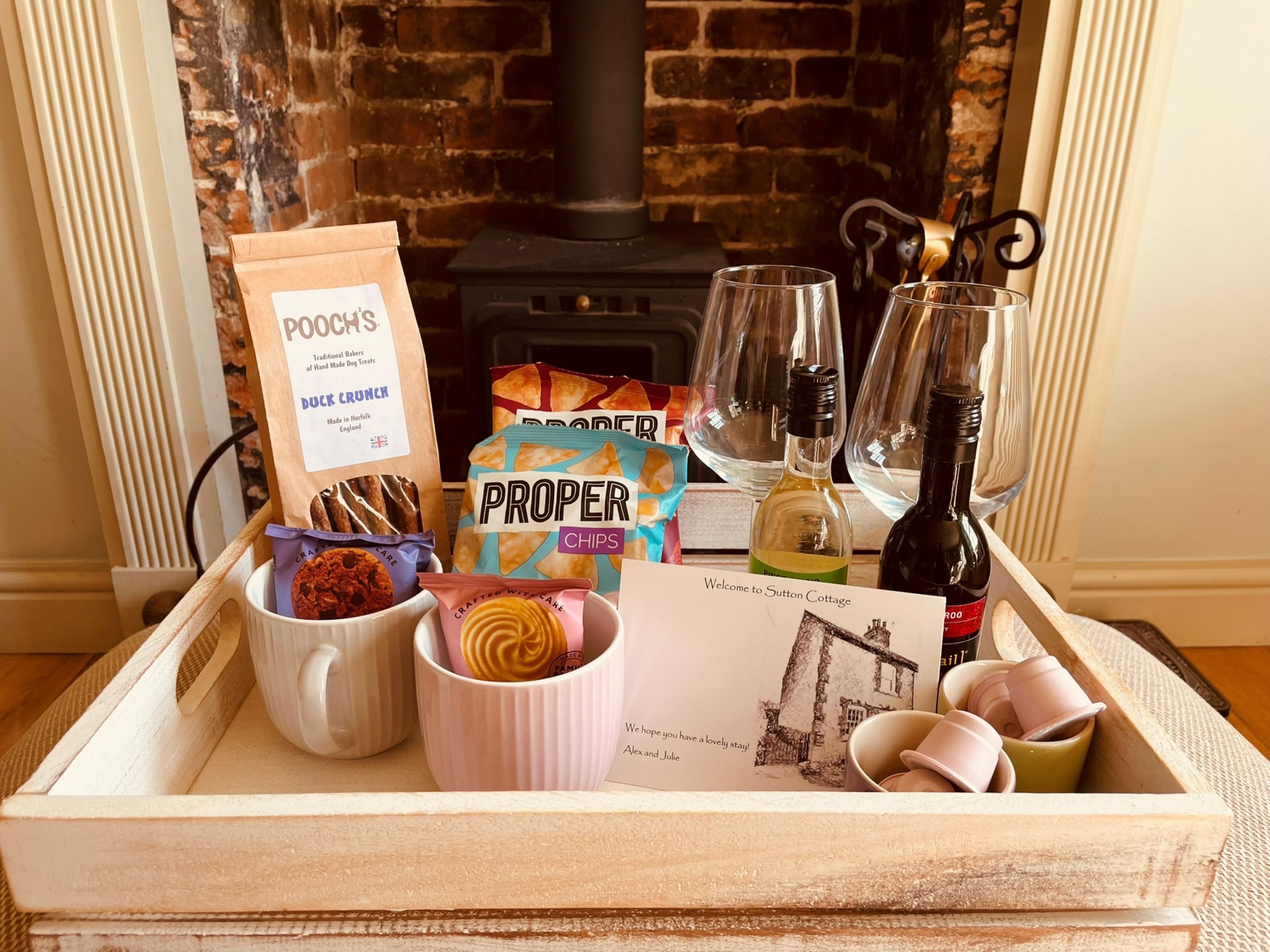 Una bandeja con aperitivos, bebidas y una nota de bienvenida en Sutton Cottage.