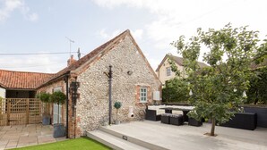 A stone house with a tiled roof, a paved patio, and outdoor seating. - The Foundry - sleeps 6 guests  in 3 bedrooms (Burnham Market)