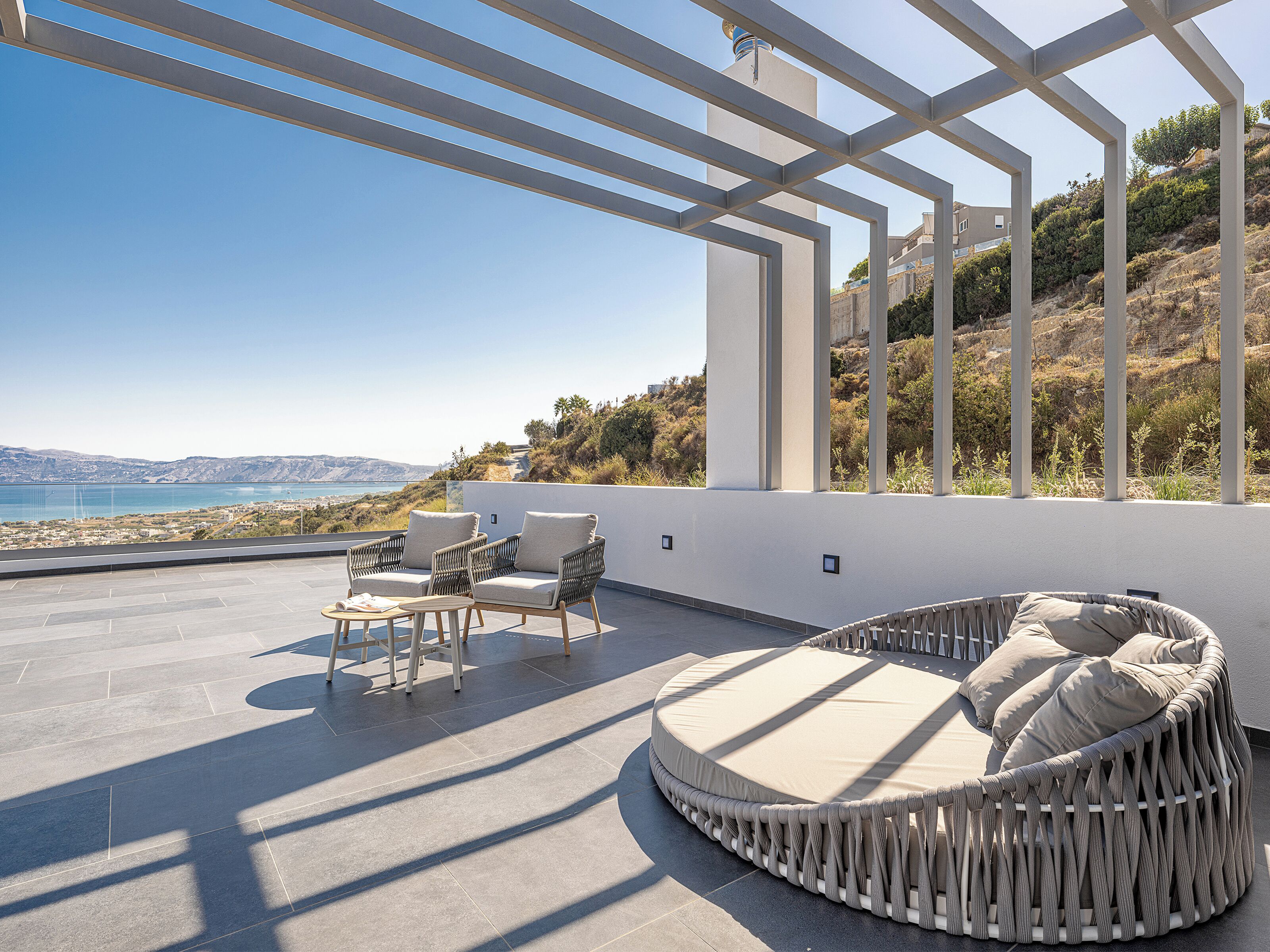 Una terraza en la azotea con una zona de estar circular, dos sillas y una mesa pequeña.