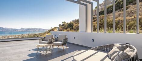 Una terraza en la azotea con una zona de estar circular, dos sillas y una mesa pequeña.